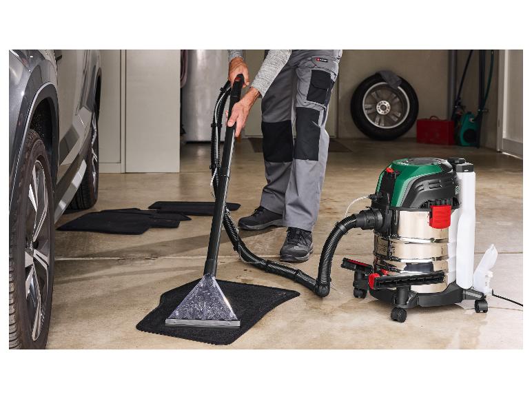 Homme nettoie les tapis de voiture avec un aspirateur Parkside dans un garage.