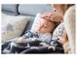 Maman vérifiant la température du bébé endormi avec une couverture étoilée.