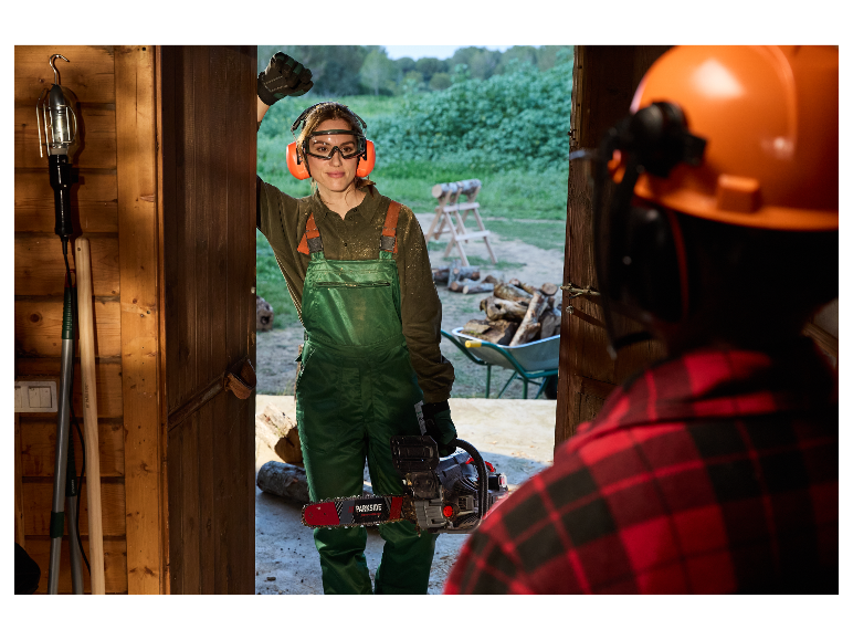 Une femme avec une tronçonneuse Parkside dans un hangar en bois.