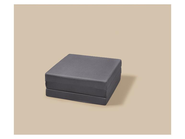 Matelas gris pliable sur fond beige.