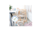 Chaise haute en bois clair avec plateau, bols et tasses colorés sur une table.