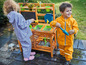 Deux enfants jouent avec de l'eau dans une cuisine en bois pour enfants.