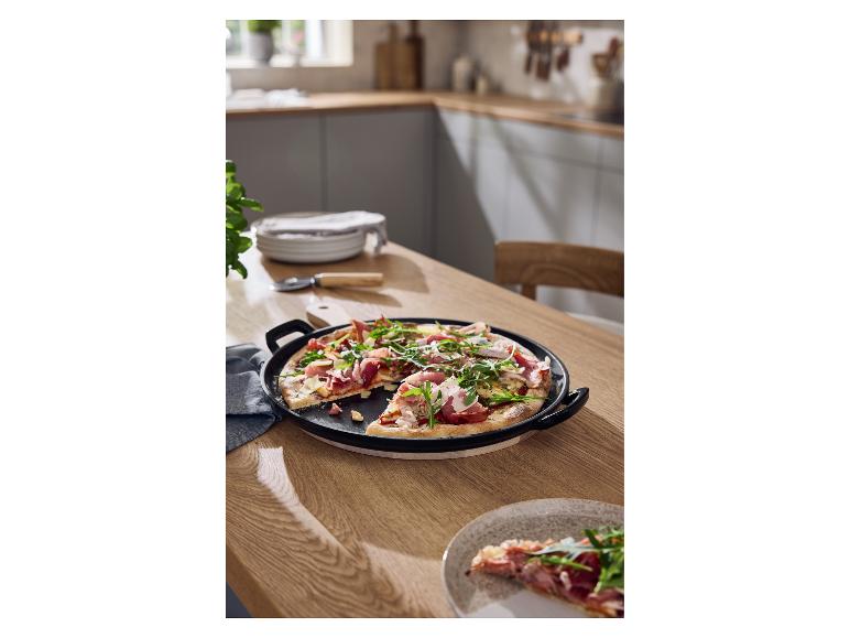 Plaque à pizza en fonte SILVERCREST® avec une pizza fraîchement cuite sur une table en bois