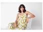 Femme assise sur une chaise blanche portant un ensemble lin vert et blanc.