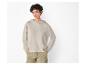 Une femme portant un sweat-shirt à capuche beige et un pantalon vert.