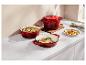 Casseroles en fonte émaillée rouge avec des repas sur un comptoir blanc dans une cuisine.