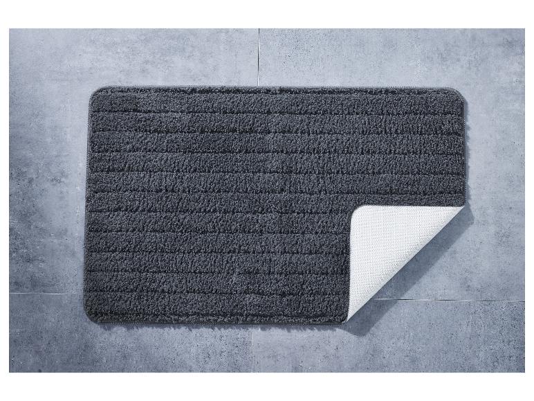 Un tapis de bain gris foncé avec une base antidérapante.