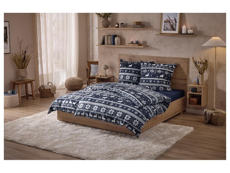 Parure de lit à motif de rennes et de flocons de neige sur un lit en bois dans une chambre douillette.