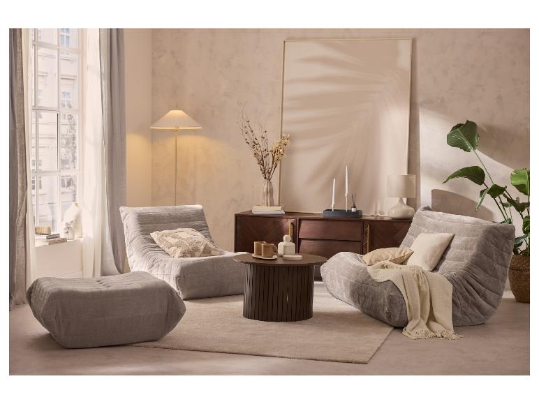 Salon avec deux fauteuils gris, un pouf, une table basse et un buffet décoré.
