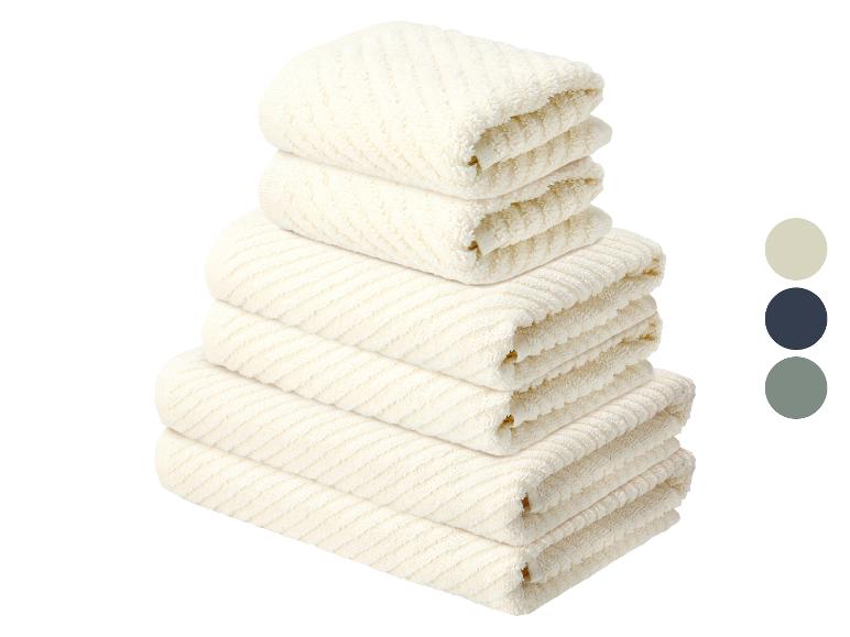 Pile de serviettes de bain blanches texturées à rayures avec échantillons de couleurs.