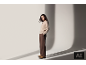 Une femme en pull beige et pantalon marron pose dans un studio