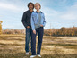 Un homme et une femme en vestes en jean et en jeans debout dans un champ.