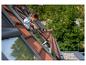 Femme nettoyant une fenêtre de toit avec un nettoyeur de vitres fixé à une perche télescopique.