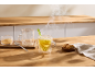 Thé au citron chaud fumant, sucre roux et biscuits sur une table en bois.