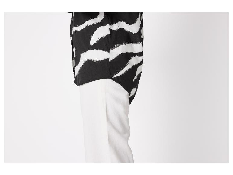 Chemise à imprimé zèbre noir et blanc et pantalon blanc.