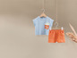 Un t-shirt bleu clair avec un imprimé de carotte et un short orange.