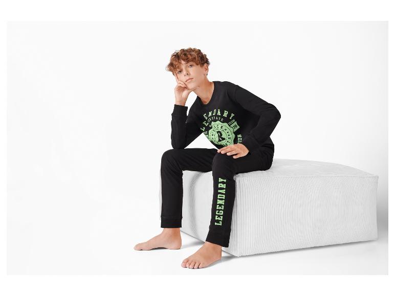Un garçon porte un pantalon de survêtement noir avec l'inscription 'Legendary' et un sweat-shirt noir avec un imprimé.
