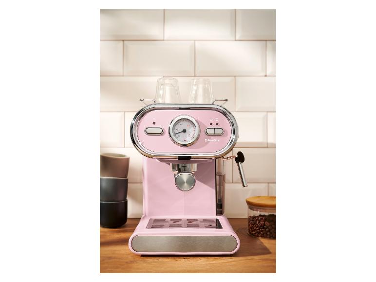 Machine à expresso rose avec tasses et grains de café sur un comptoir en bois.
