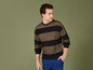 Homme portant un pull rayé noir et or avec un jean bleu.
