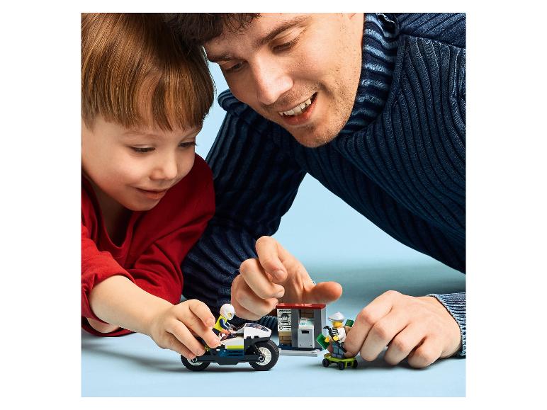 Père et fils jouent avec la moto de police LEGO City et des figurines de voleurs.