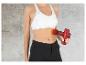 Une femme tenant un pistolet de massage Vitalmaxx rouge.