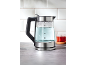 Bouilloire électrique en verre avec de l'eau et une tasse de thé sur un comptoir de cuisine.