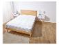 Un protège-matelas blanc sur un cadre de lit en bois.