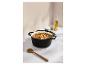 Cocotte en fonte noire remplie de ragoût sur un comptoir en marbre avec une cuillère en bois.