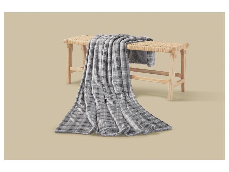 Couverture grise à carreaux drapée sur un banc en bois.