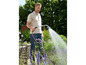 Un homme arrose des plantes dans son jardin avec un tuyau d'arrosage Gardena.