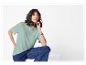 Femme modelant un t-shirt vert clair et un jean.