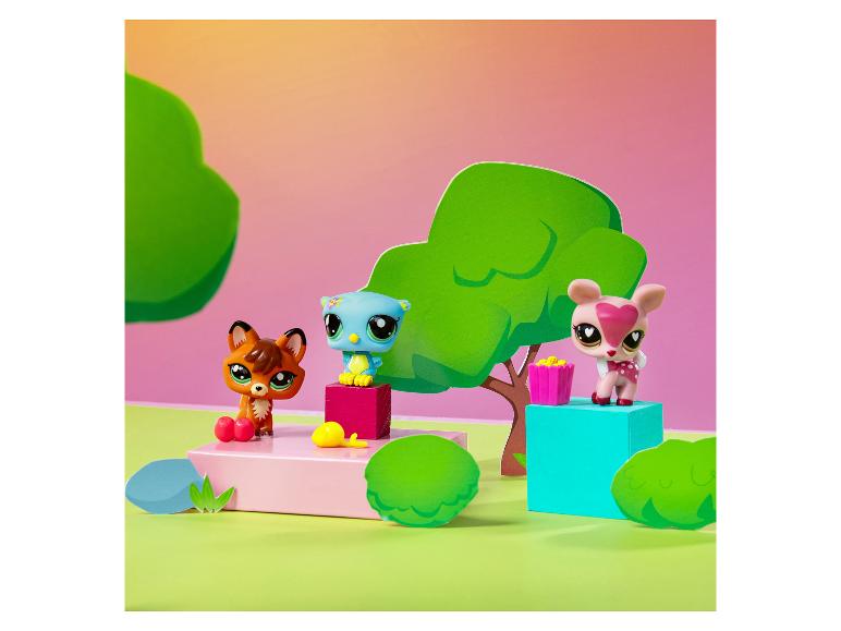 Trois figurines d'animaux Littlest Pet Shop, un renard, un hibou et un cerf, dans un décor forestier stylisé.