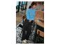 Une femme portant un pull bleu et un pantalon noir travaille sur un ordinateur portable dans un café.