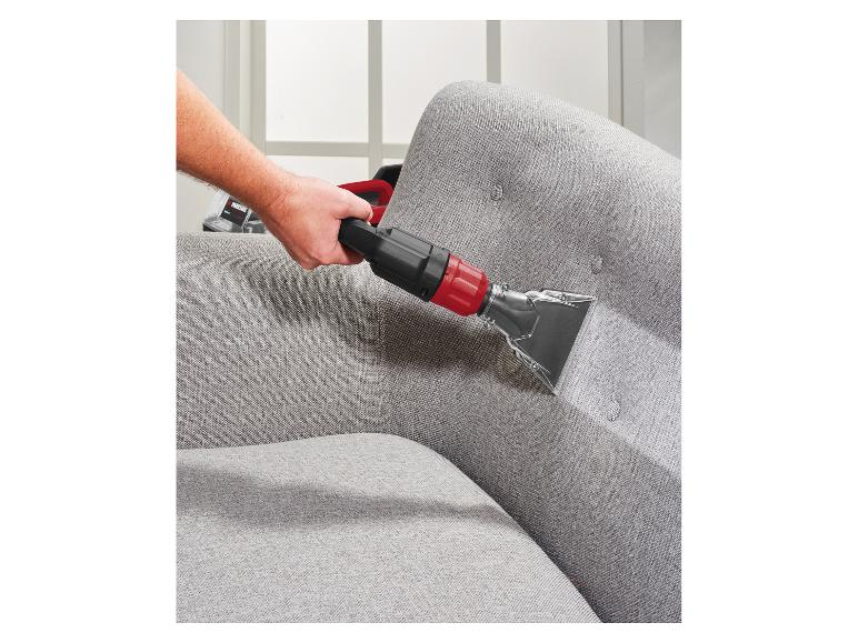 Homme nettoyant un canapé gris avec un nettoyeur de tissus d'ameublement.