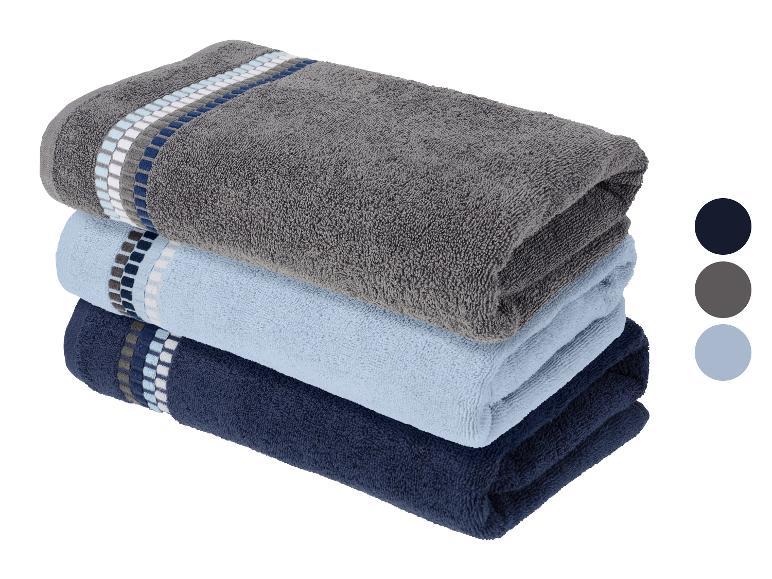 Serviettes empilées en gris, bleu clair et bleu foncé avec des rayures décoratives.