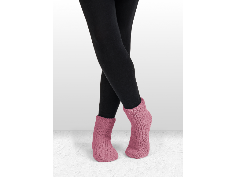 Jambes en leggings noirs et chaussettes-chaussons roses tricotées.