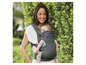 Une femme porte un bébé dans un porte-bébé Infantino.