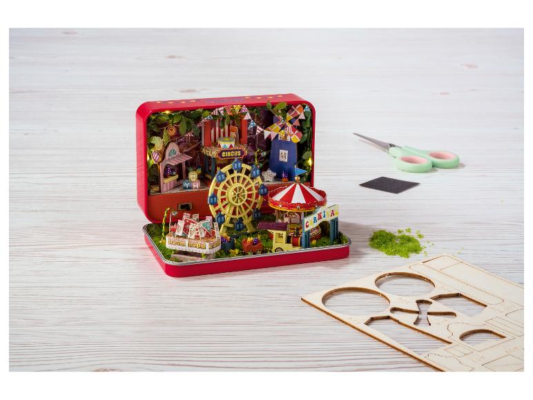 Diorama de carnaval dans une boîte métallique rouge, avec accessoires à assembler.