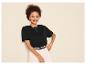 Femme souriante en t-shirt noir et pantalon clair.