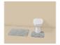 Tapis de bain gris et toilettes blanches dans une salle de bain beige.