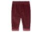 Pantalon en velours côtelé bordeaux avec des pois blancs sur les ourlets.