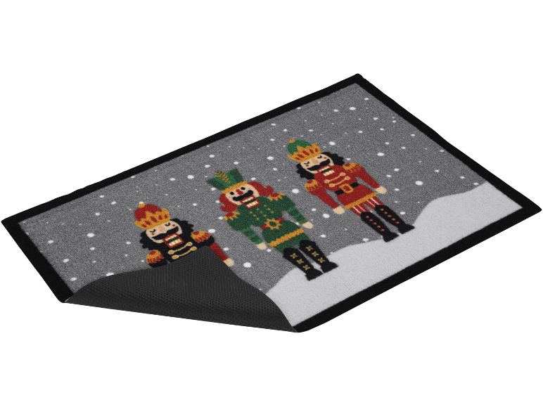 Tapis de Noël avec trois figurines de casse-noisettes dans un paysage enneigé.