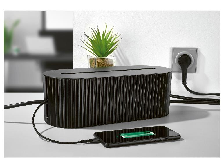 Un boîtier de câbles noir avec un téléphone en charge.