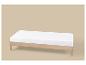 Lit en bois avec matelas blanc sur fond beige.