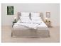 Aménagement de chambre avec literie blanche et lit gris, avec des accents verts et beiges.
