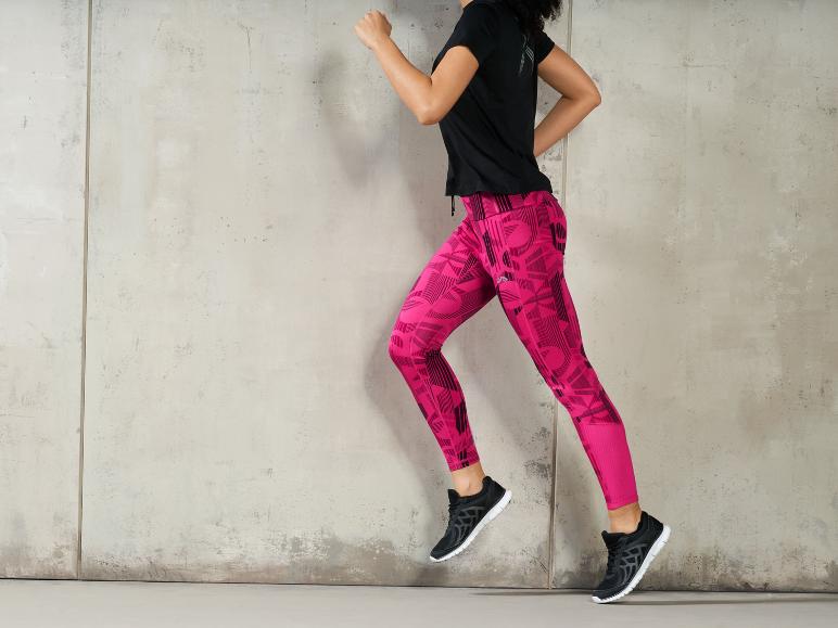 Une femme porte un legging rose et des baskets noires.