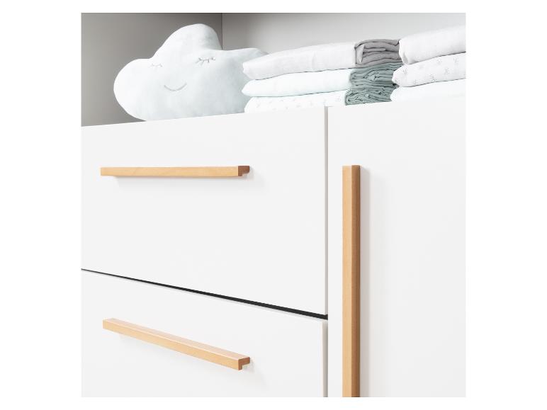 Commode blanche avec poignées en bois et un oreiller en forme de nuage avec de la literie.