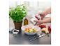 Une personne râpant du fromage sur un plat de pâtes aux tomates cerises et basilic, avec de l'huile d'olive et des épices.