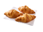 Trois croissants dorés sur une serviette blanche, prêts à être dégustés.