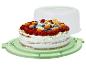 Gâteau fruité à la crème fouettée et aux baies sur un plat à gâteau vert avec couvercle.